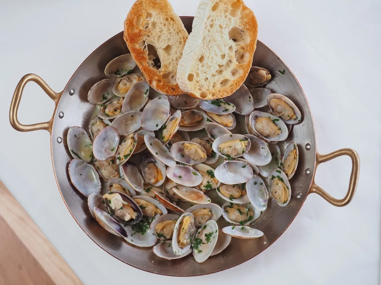 Amêijoas à Bulhão Pato : palourdes à l'ail et à la coriandre dans un plat en cuivre avec du pain grillé