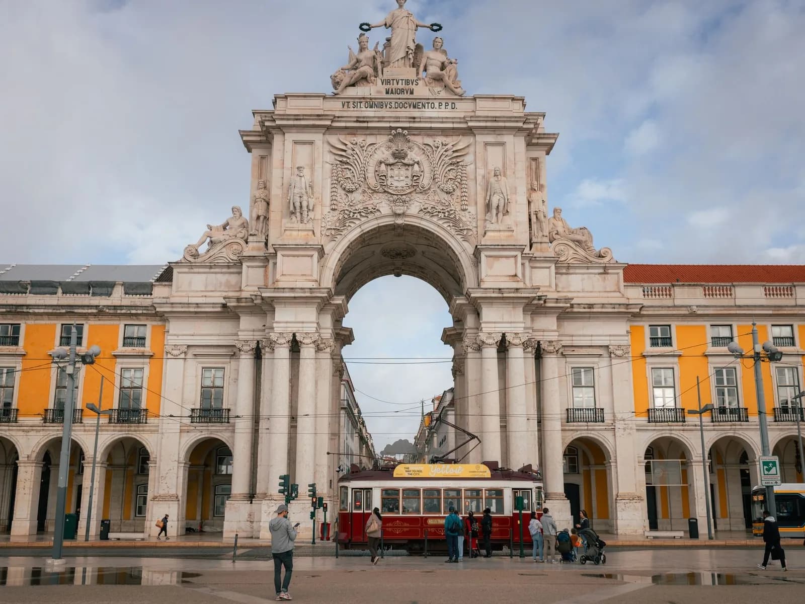 L'Arco da Rua Augusta vu depuis la Praça do Comércio, avec son horloge, son groupe sculpté au sommet et un tramway rouge dessous
