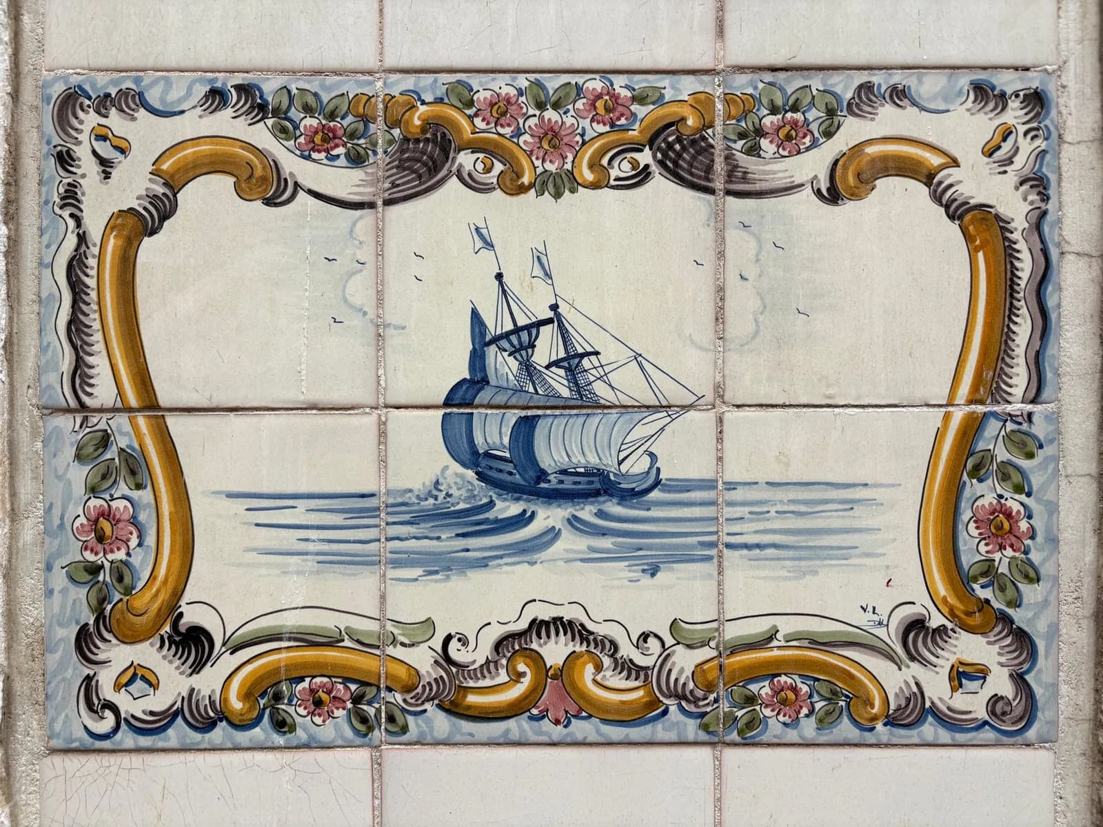 Panneau d'azulejos bleus représentant une caravelle, dans un cadre baroque jaune