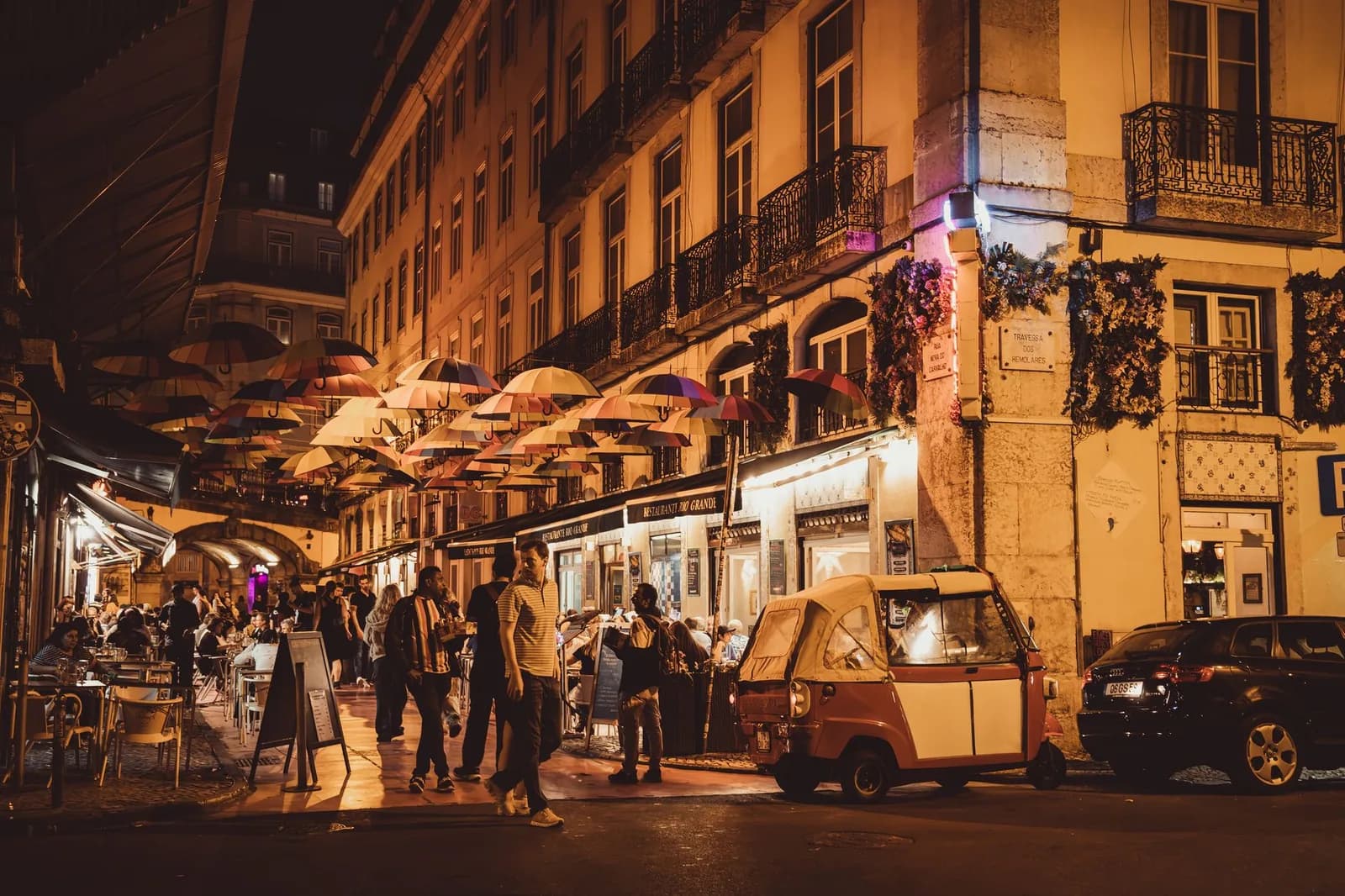 Rue de Lisbonne la nuit, terrasses éclairées et groupe de personnes attablées dehors