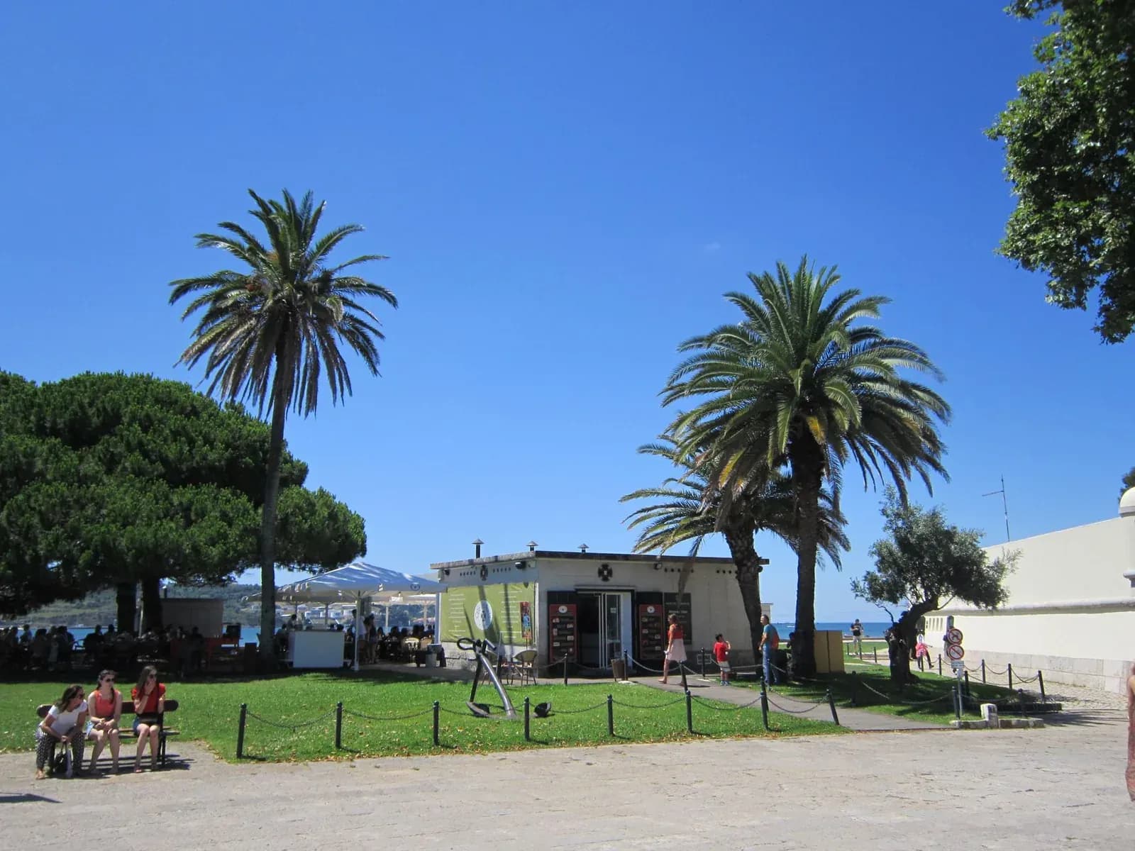 Un parc ensoleillé au bord du Tage à Belém, à Lisbonne, avec ses palmiers et ses bancs