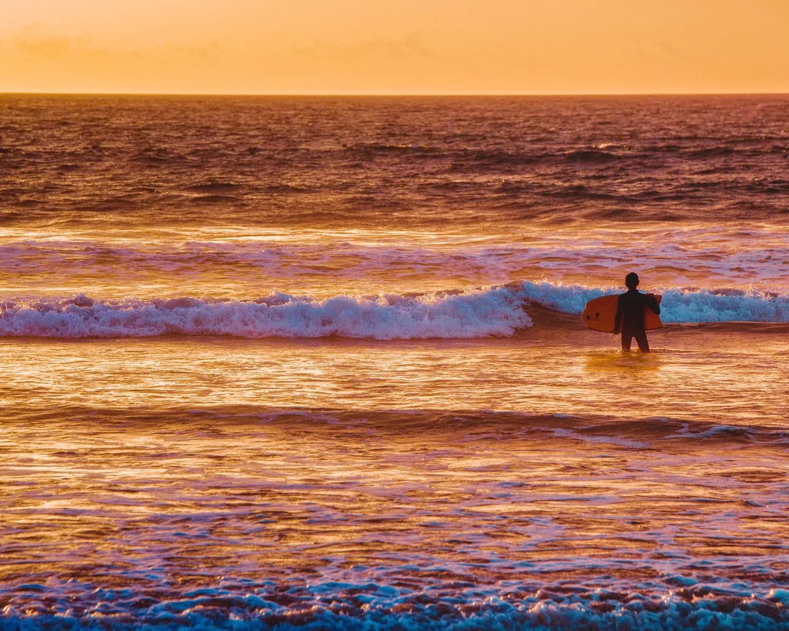 Un surfeur au coucher du soleil sur une plage de la Costa da Caparica, au sud de Lisbonne