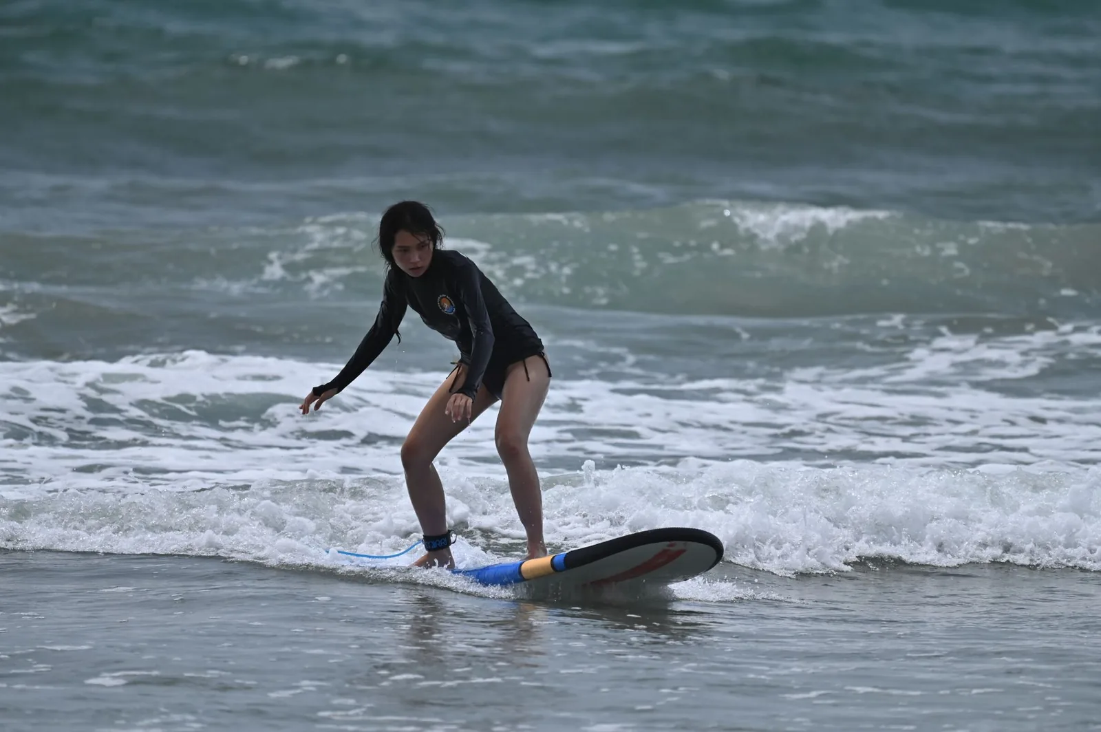 Surfeuse débutante debout sur sa planche dans la mousse