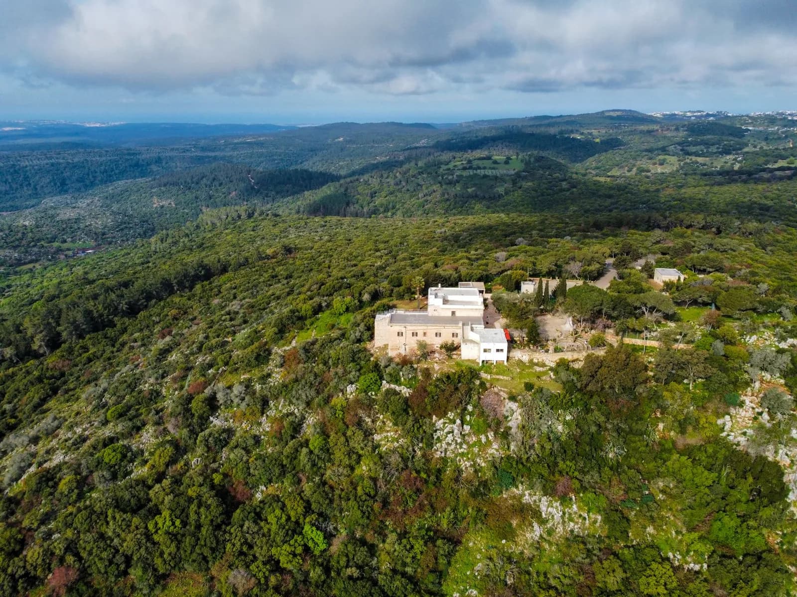 Bâtiments blancs d'un couvent isolé sur un versant boisé de la serra