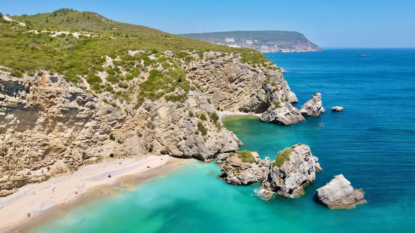 Petite crique de sable clair et eau turquoise entre les rochers calcaires de la côte de l'Arrábida
