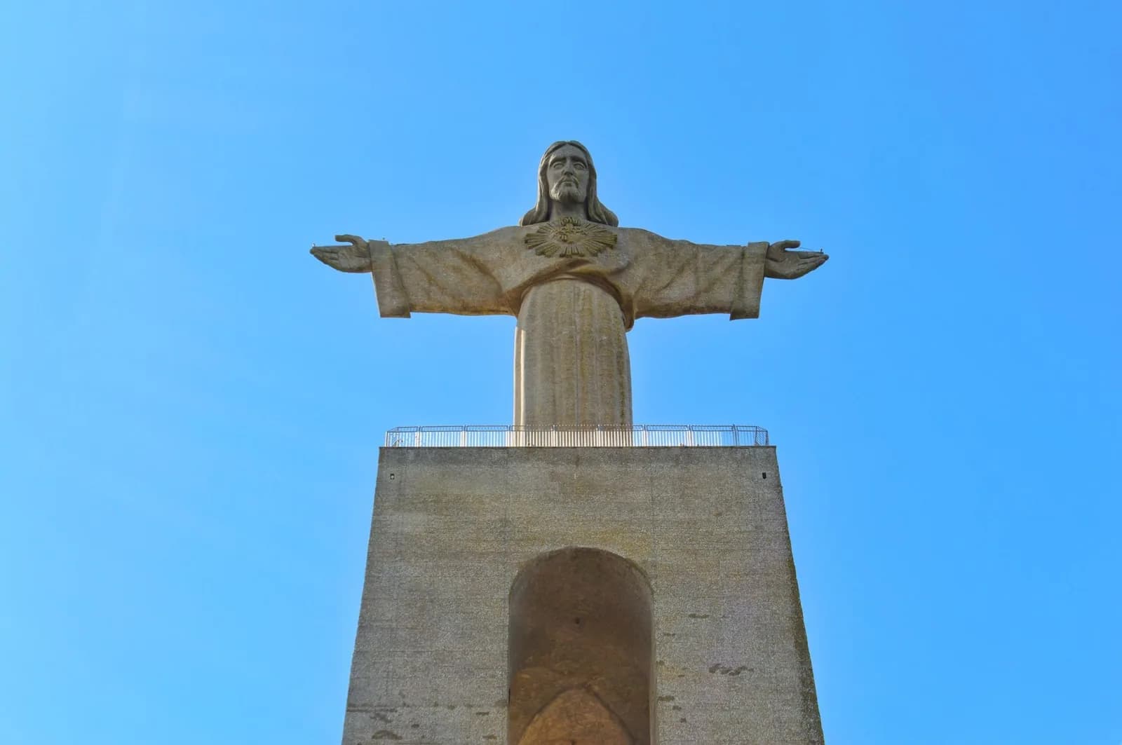 La statue du Christ-Roi d'Almada, bras ouverts, sur son haut piédestal en béton
