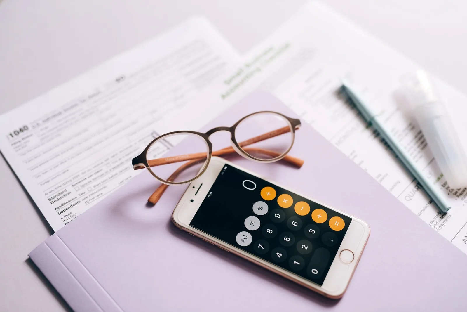 Formulaires, lunettes et calculatrice de téléphone posés sur un bureau