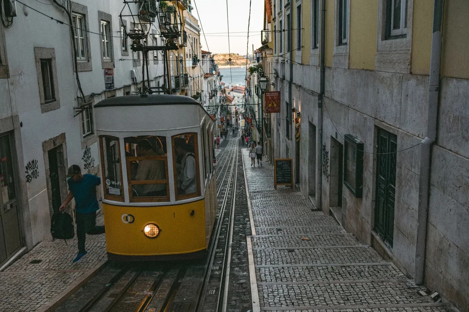Le funiculaire de la Bica descendant une rue pavée de Lisbonne vers le Tage au coucher du soleil