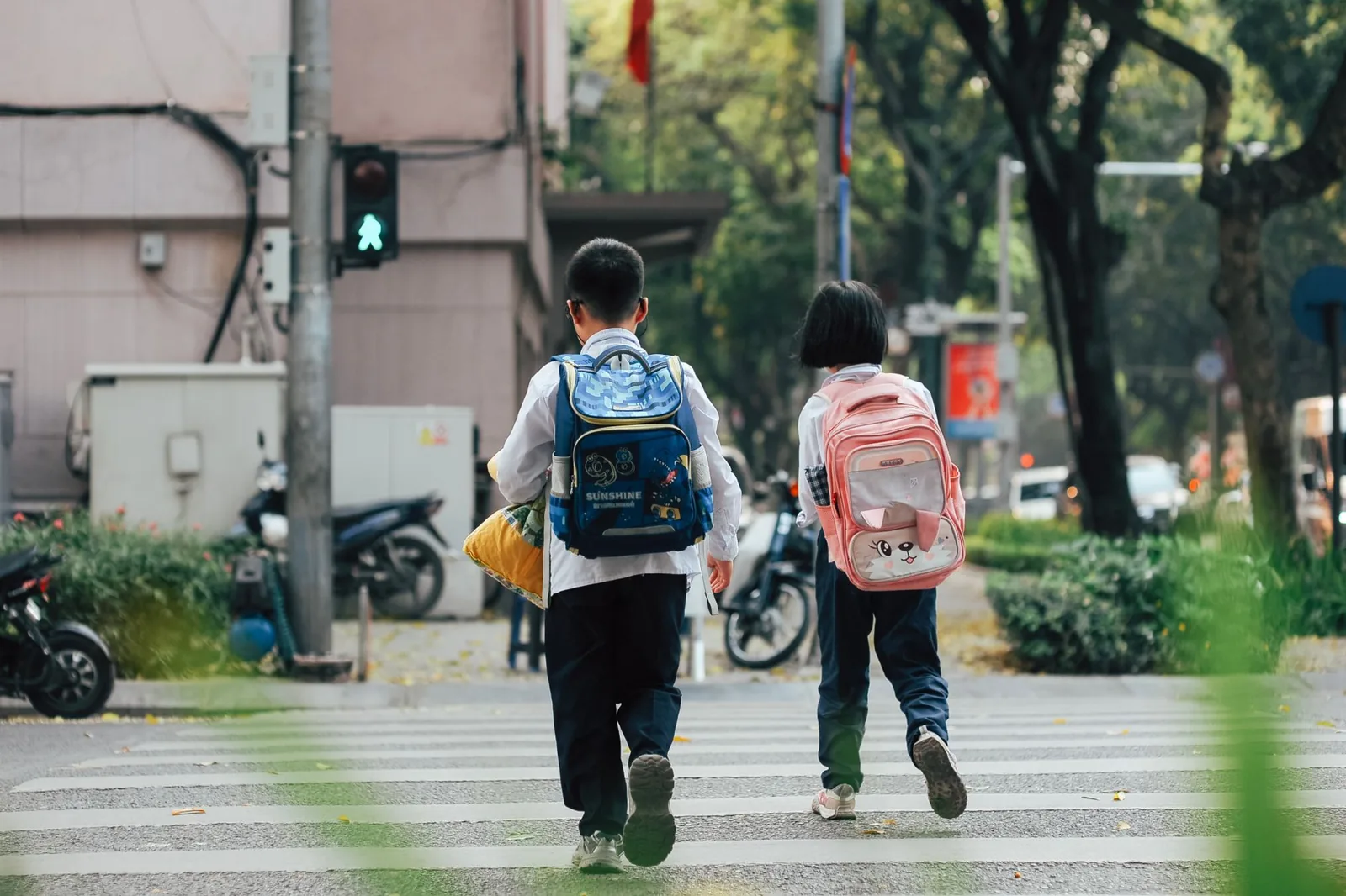 Deux enfants avec leur cartable traversent une rue