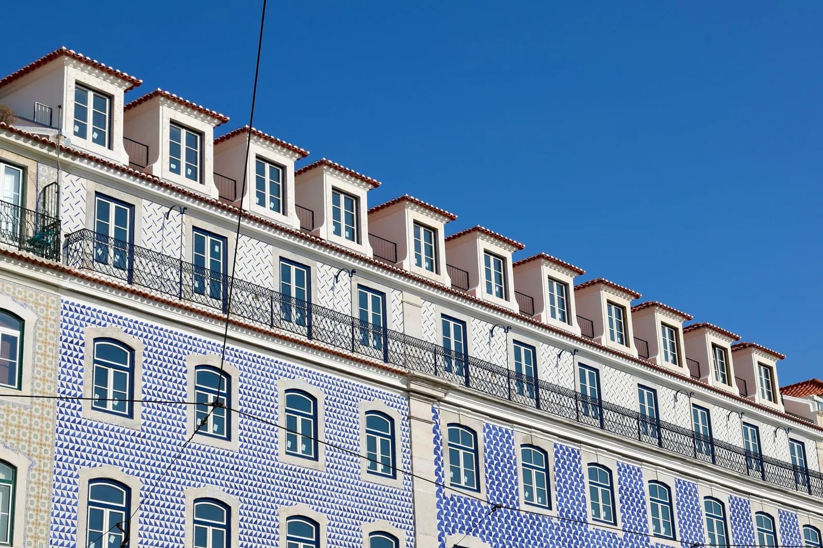 Façade d'immeuble de Lisbonne couverte d'azulejos bleus, rangée de fenêtres sous un ciel bleu