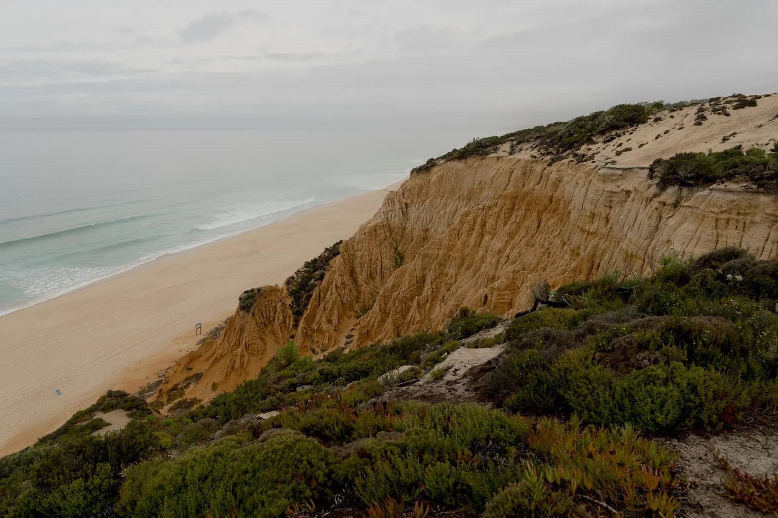 Falaises de grès ocre au-dessus d'une longue plage de sable