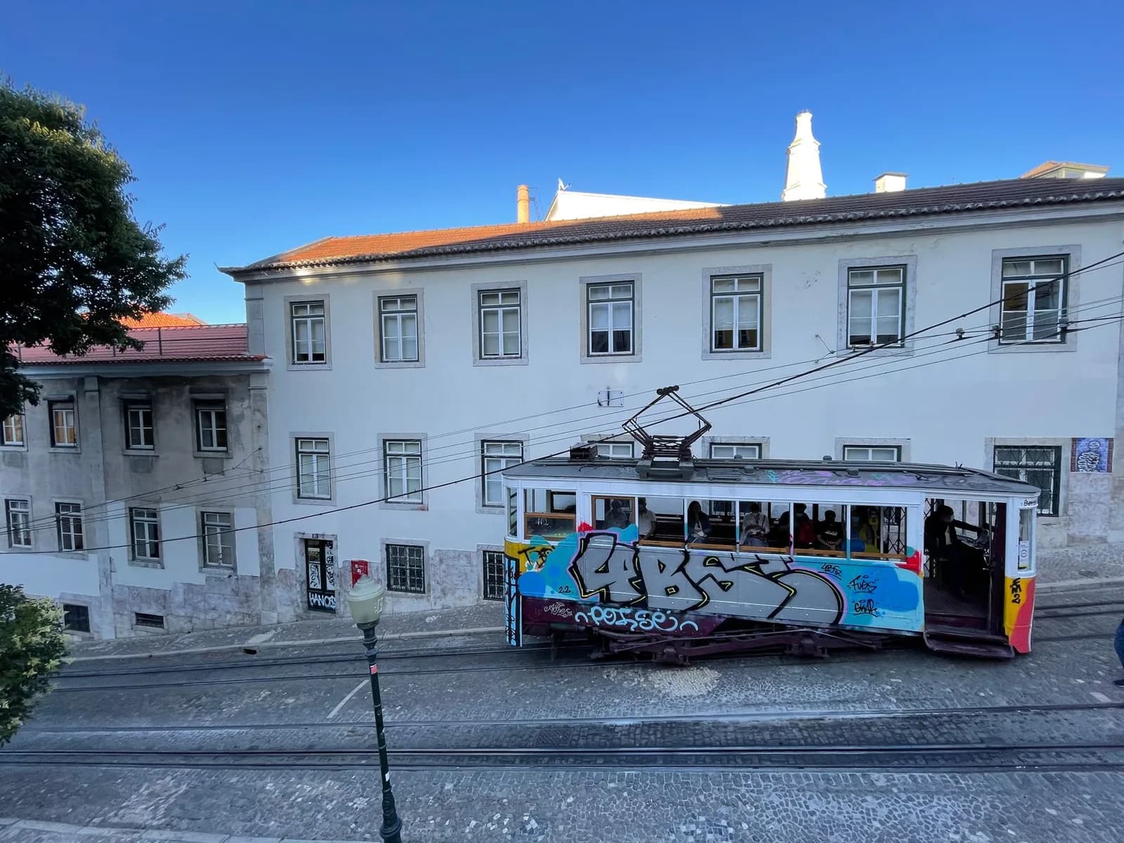 Funiculaire couvert de graffitis dans une rue en pente de Lisbonne