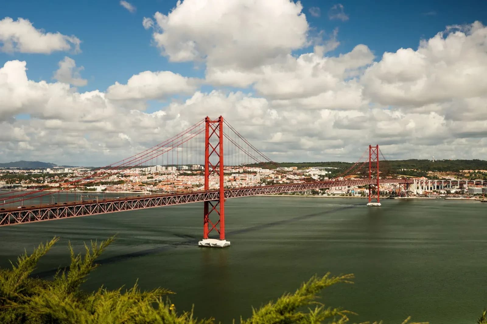 Le pont du 25 Avril, rouge, enjambant le Tage devant les toits de Lisbonne à l'arrivée