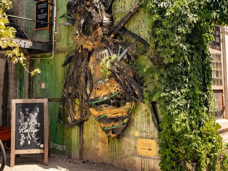 L'abeille géante en matériaux de récupération de Bordalo II sur un mur vert de la LX Factory, Lisbonne