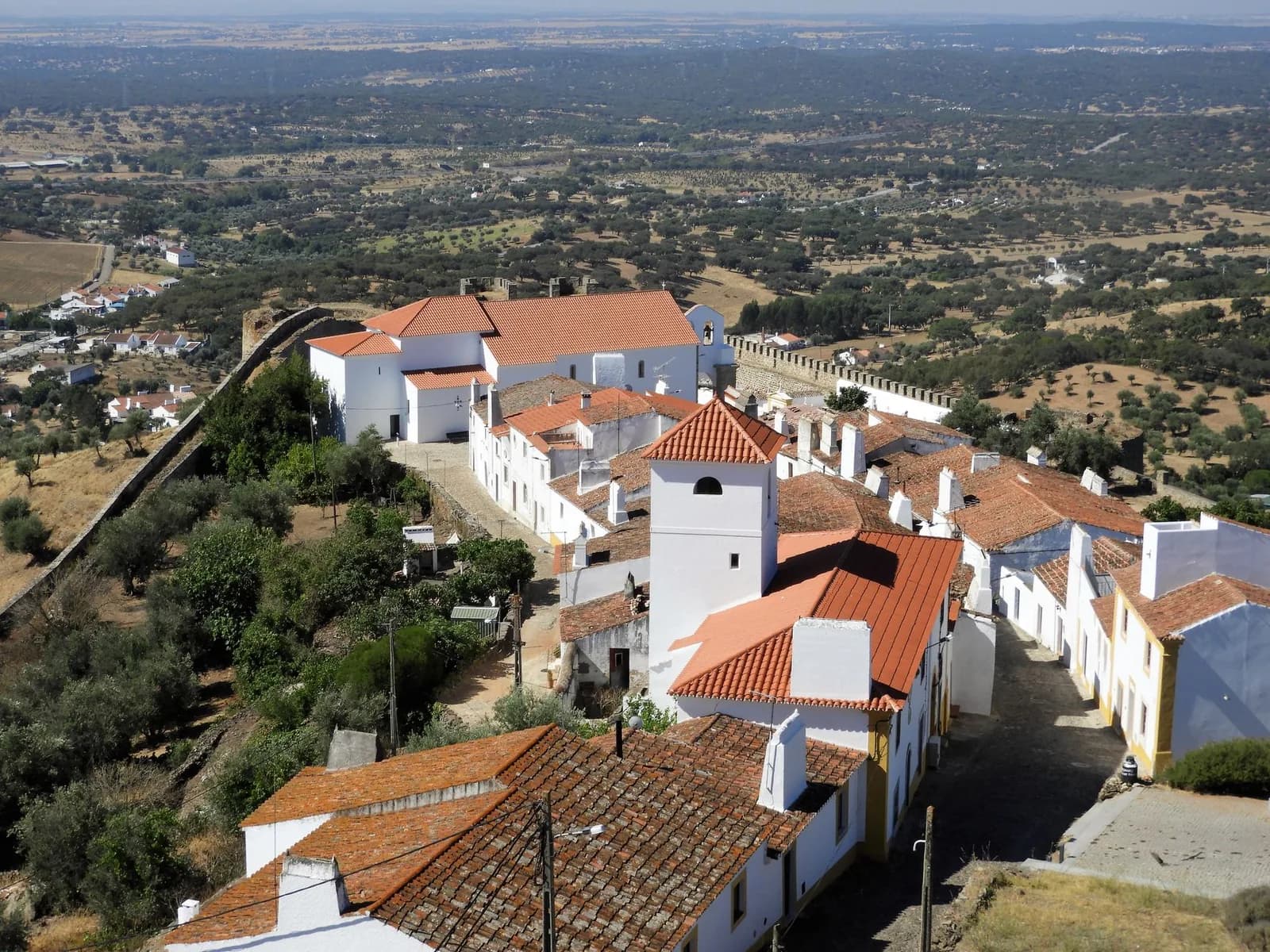 Village blanc de l'Alentejo aux toits de tuiles orange, entouré de plaines d'oliviers et de chênes-lièges