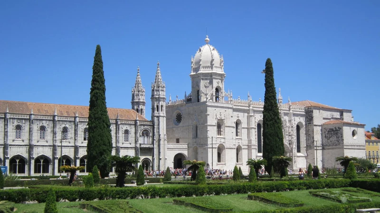 Façade du monastère des Hiéronymites à Belém, vue depuis les jardins de la Praça do Império sous un ciel bleu