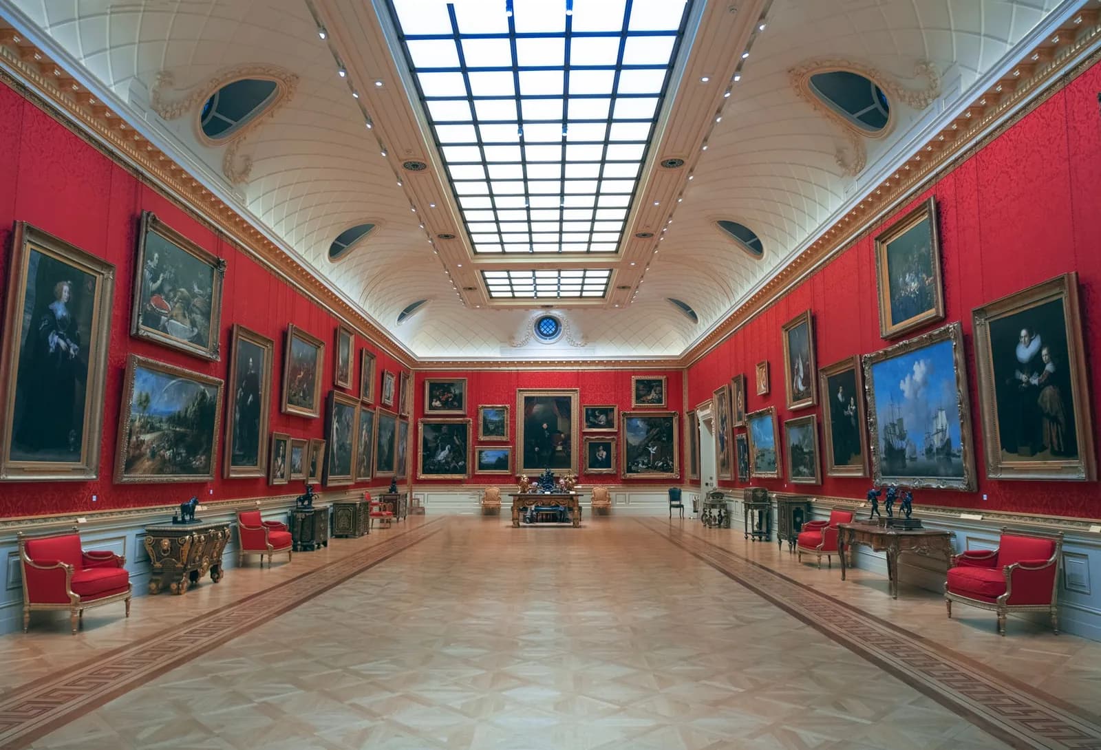 Galerie de musée aux murs rouges couverts de peintures anciennes