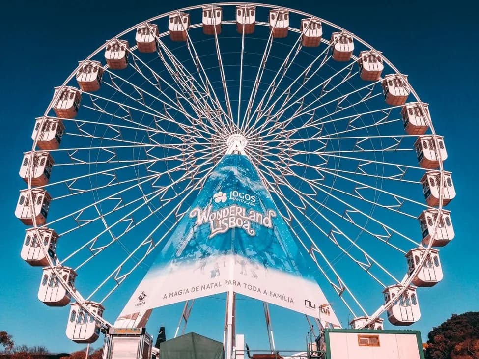 Grande roue du Wonderland Lisboa sous un ciel bleu, avec la bannière « A magia de Natal para toda a família »