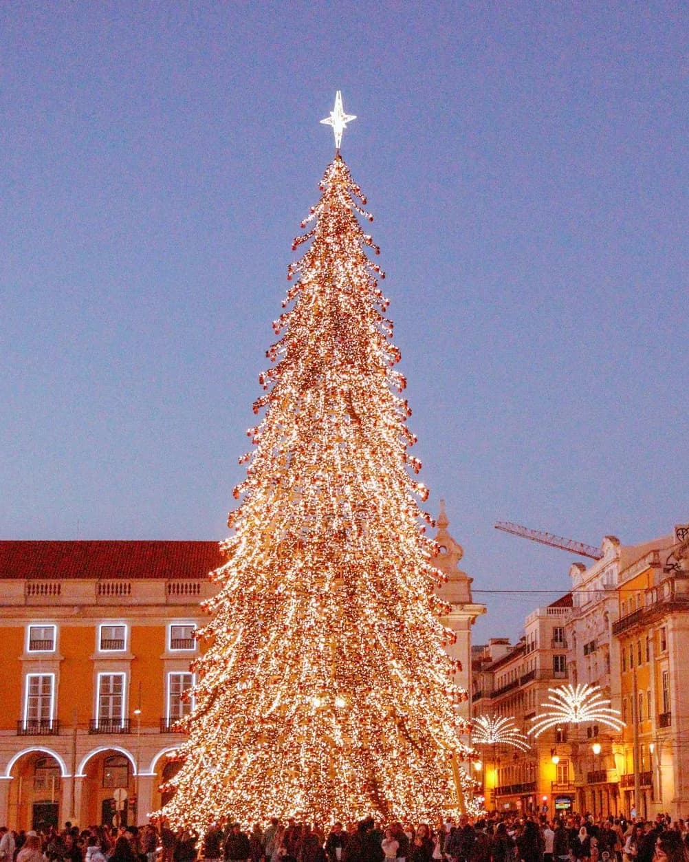 Sapin de Noël géant couvert de lumières sur la Praça do Comércio à Lisbonne, devant les façades de la place au crépuscule