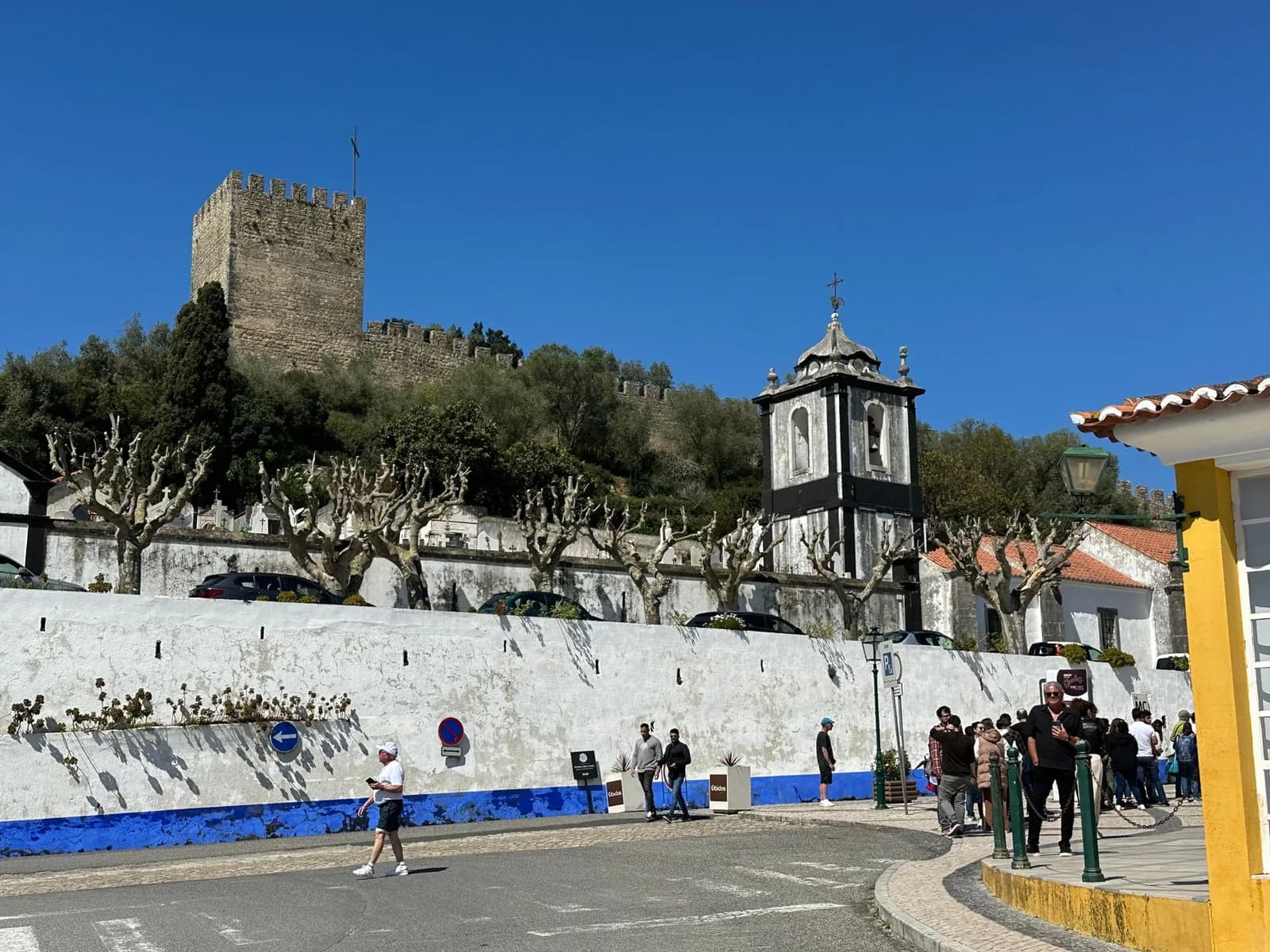 Clocher blanc et tour du château d'Óbidos au-dessus d'un mur blanc et bleu