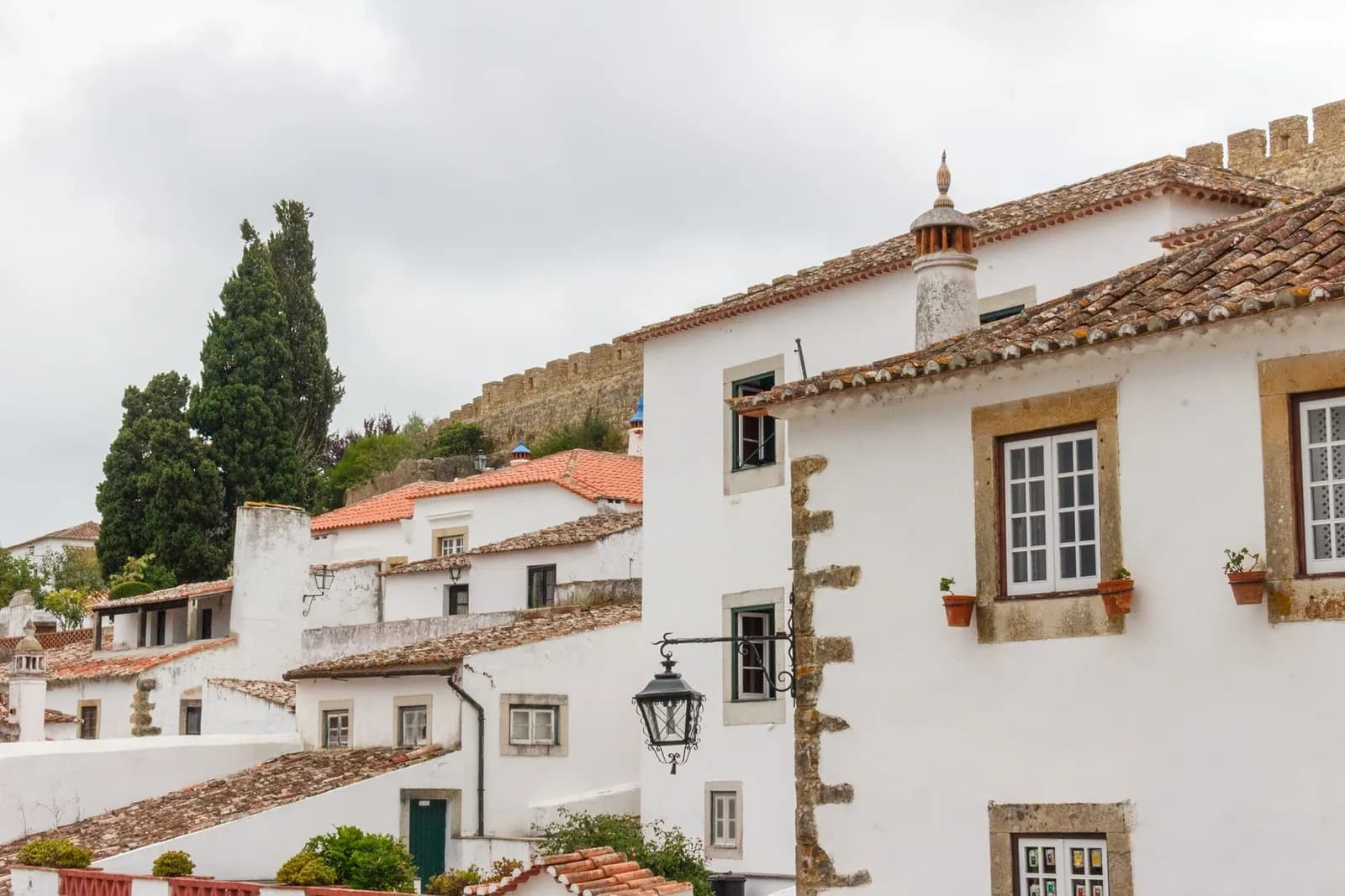 Maisons blanches à encadrements de pierre et toits de tuiles d'Óbidos, au pied des remparts