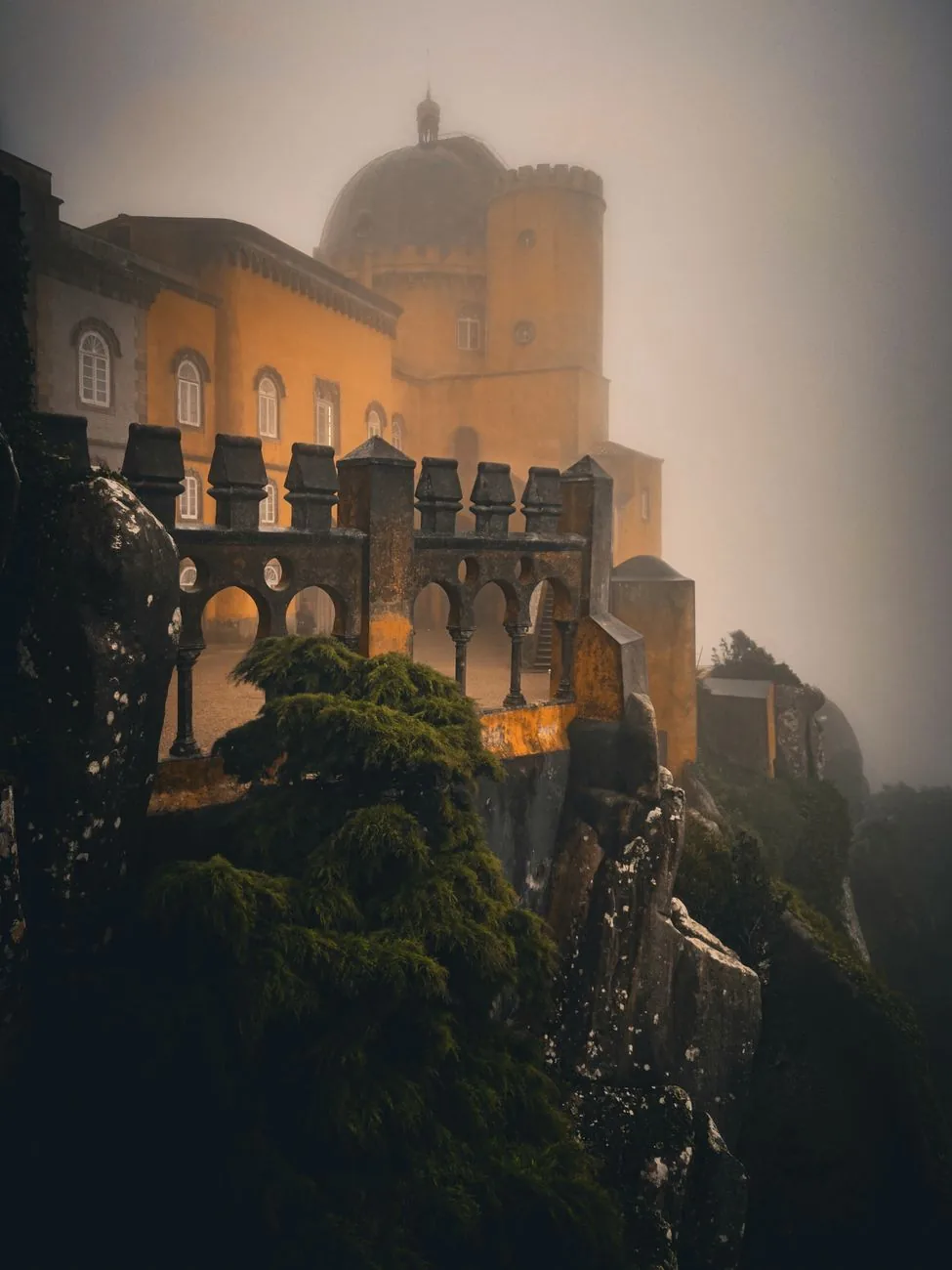 Le palais de Pena émergeant de la brume au-dessus de la végétation, à Sintra