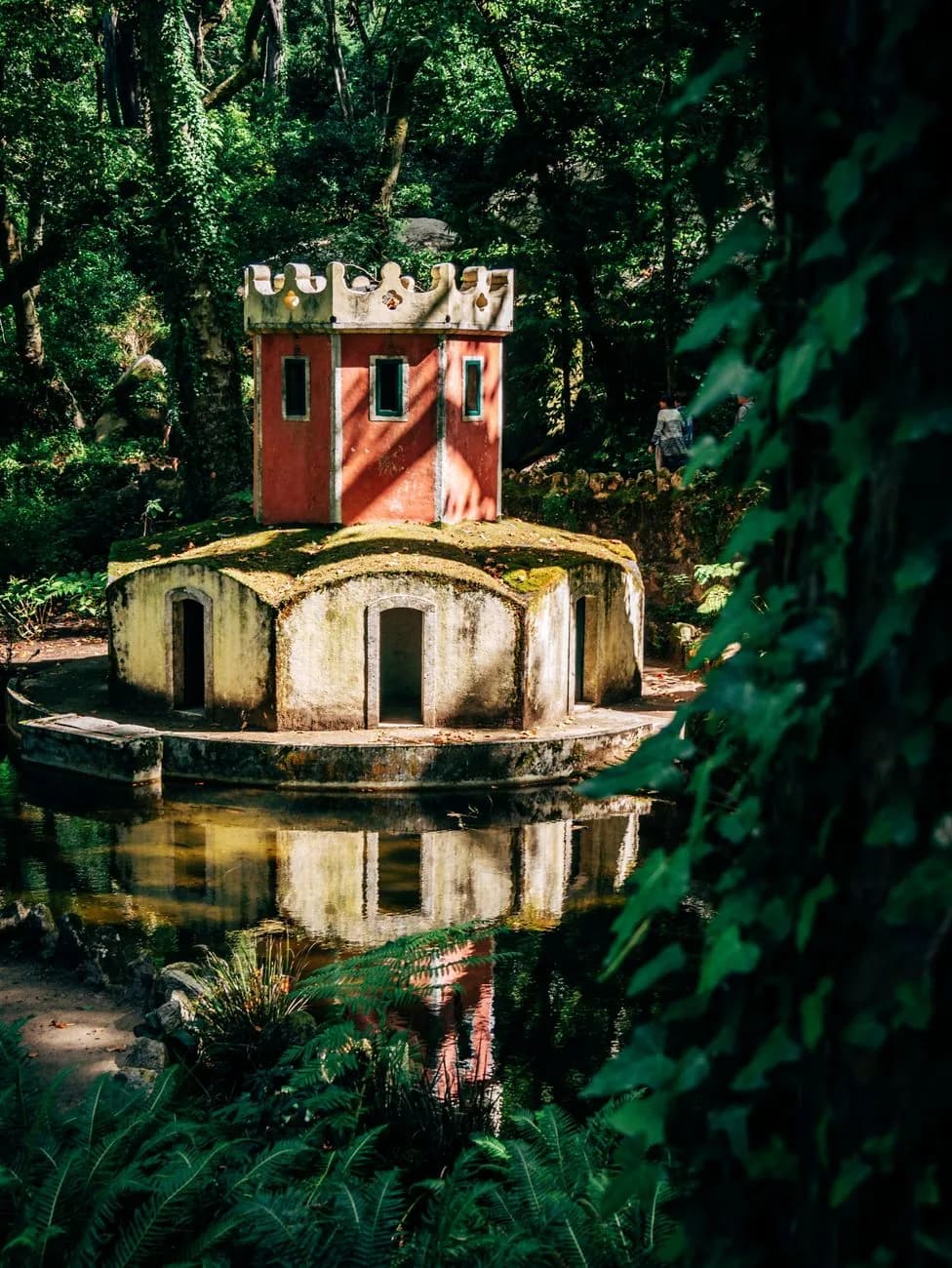 Petit pavillon à tour crénelée rouge au bord d'un étang, dans la végétation dense du parc de Pena