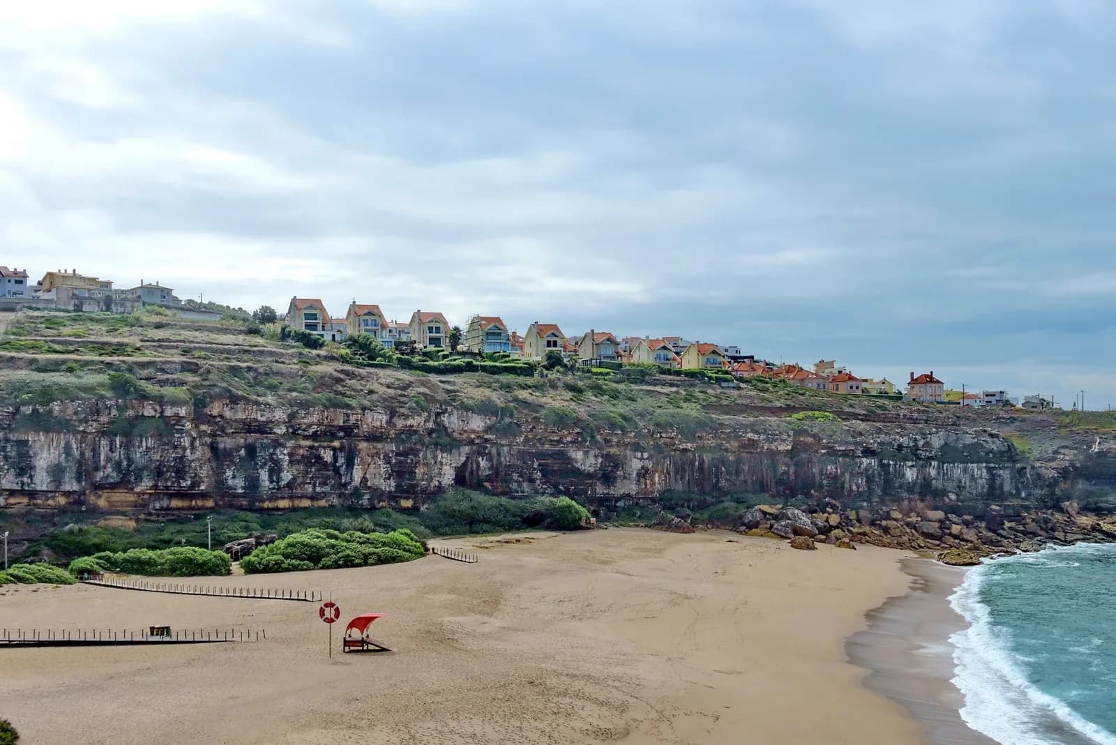 Plage de sable au pied des falaises, maisons sur le plateau