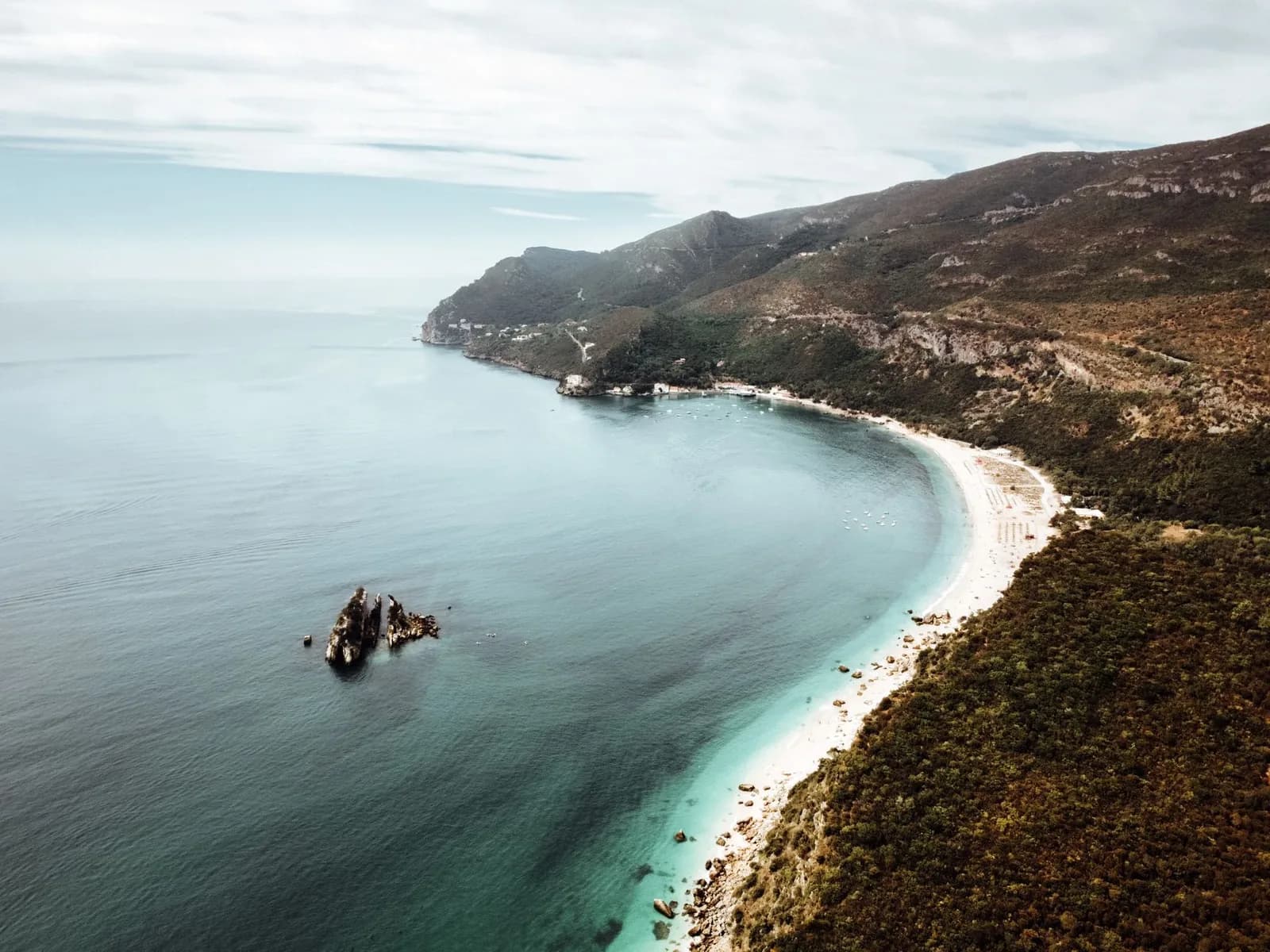 Longue plage de sable clair au pied des pentes de la serra, vue d'en haut