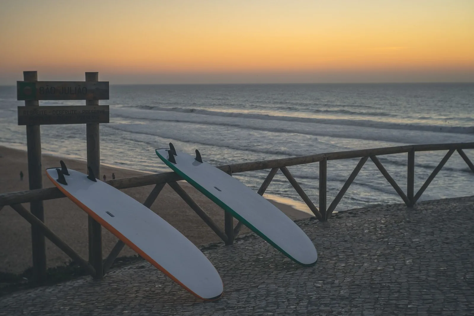 Planches de surf posées contre une rambarde face à l'océan