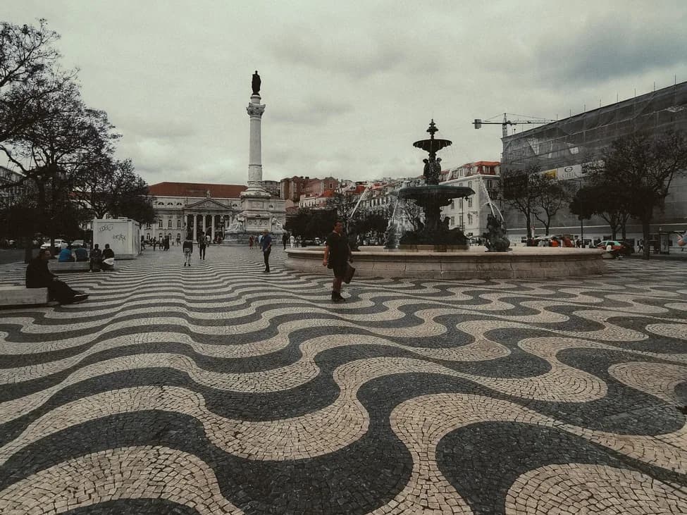 Place pavée de calçada portugaise aux vagues noires et blanches, avec colonne et fontaine