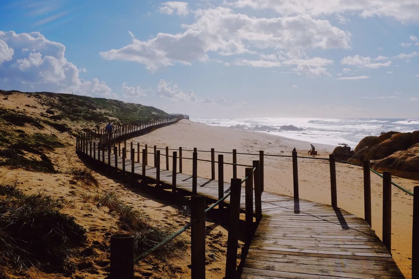 Passerelle en bois sinueuse à travers les dunes menant à une plage de la côte portugaise