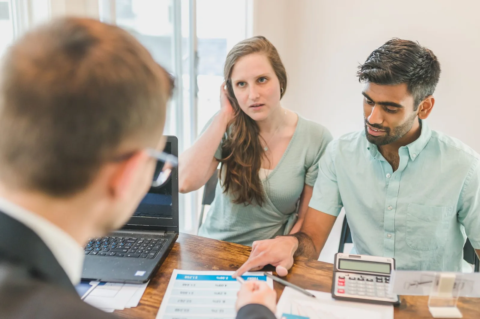 Couple en rendez-vous avec un conseiller, calculatrice et documents sur la table