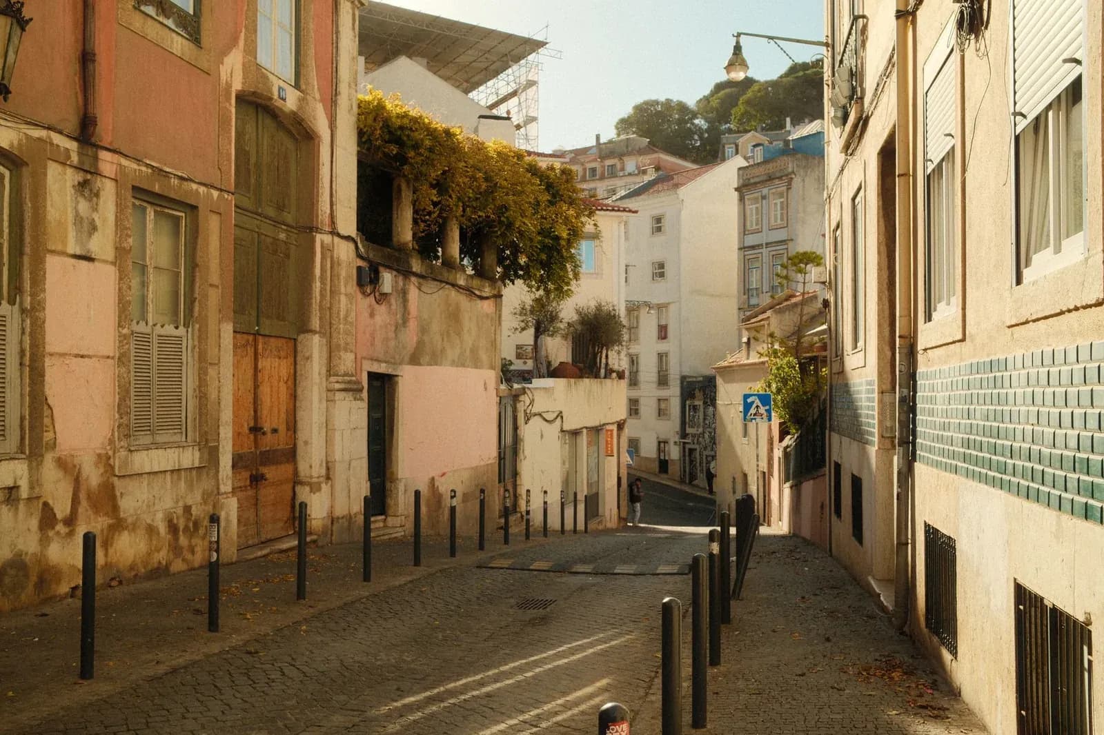 Rue résidentielle pavée aux façades pastel dans un quartier de Lisbonne, sous la colline du château