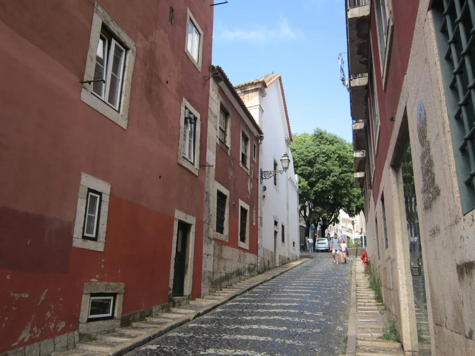 Ruelle pavée aux façades ocre-rouge d'un quartier de Lisbonne, un jour ensoleillé