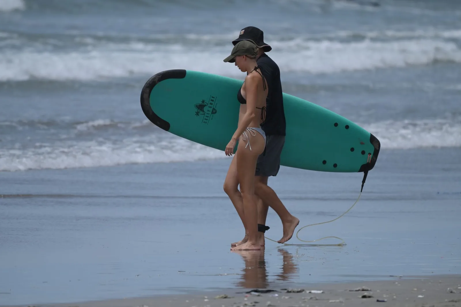 Surfeurs portant leur planche au bord de l'eau sur une plage