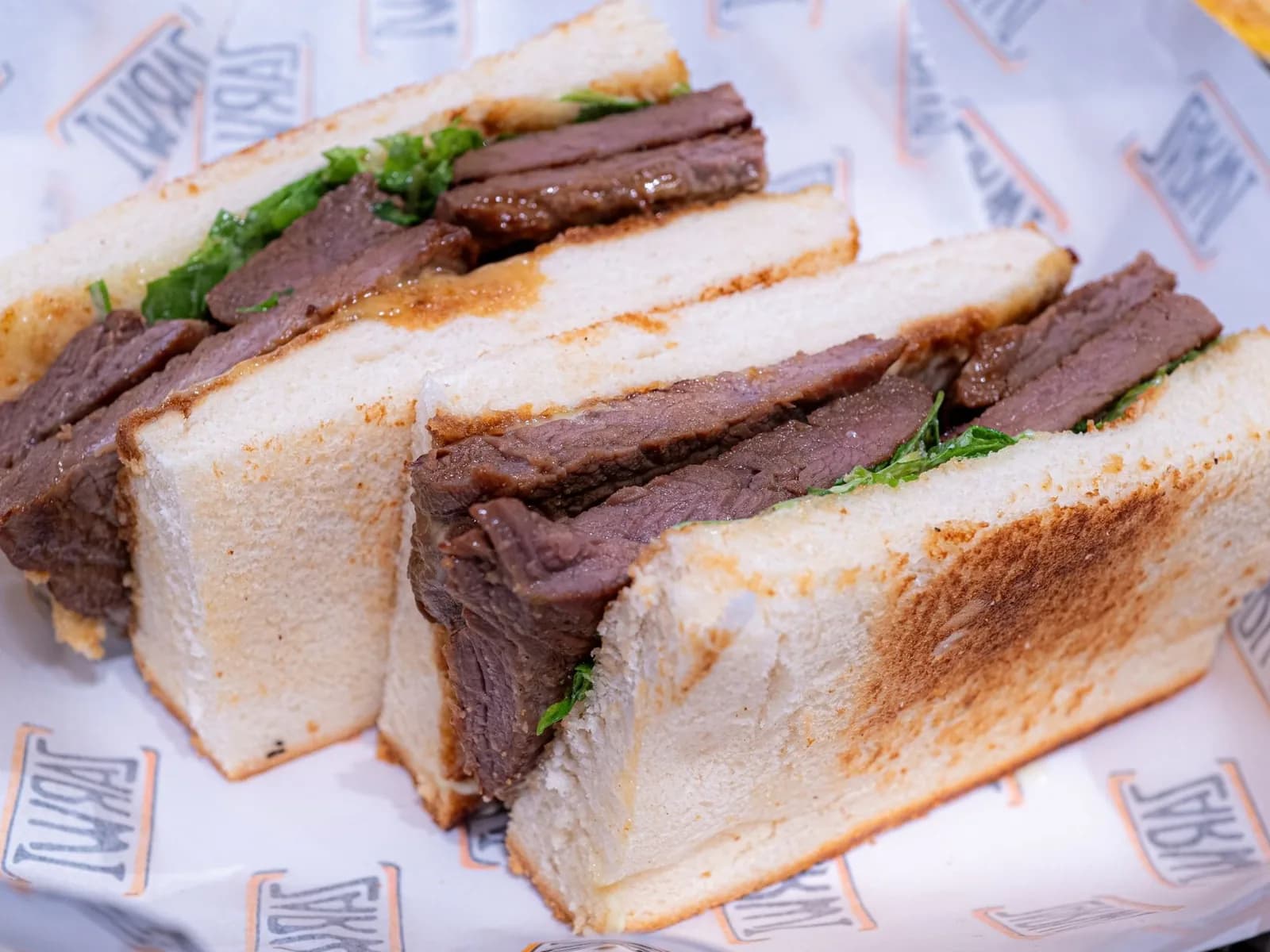 Sandwich au steak de bœuf tranché avec salade et pain grillé