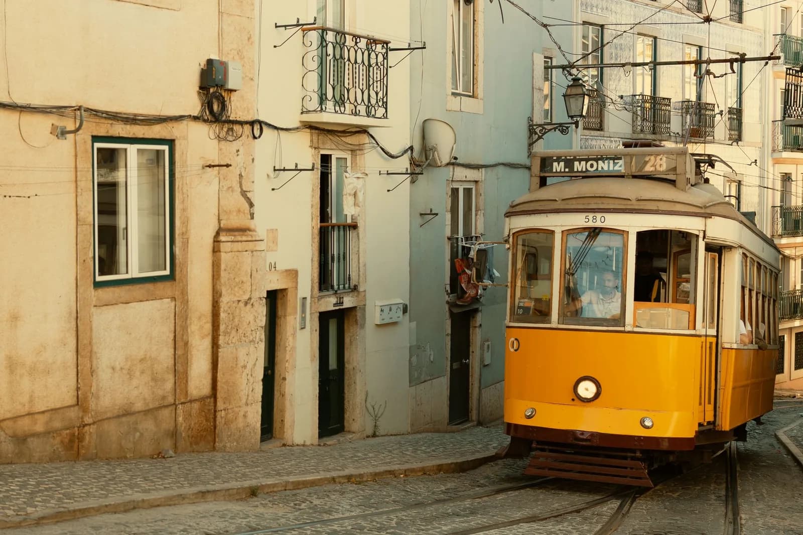 Tramway jaune de la ligne 28, direction Martim Moniz, dans une rue pavée de Lisbonne