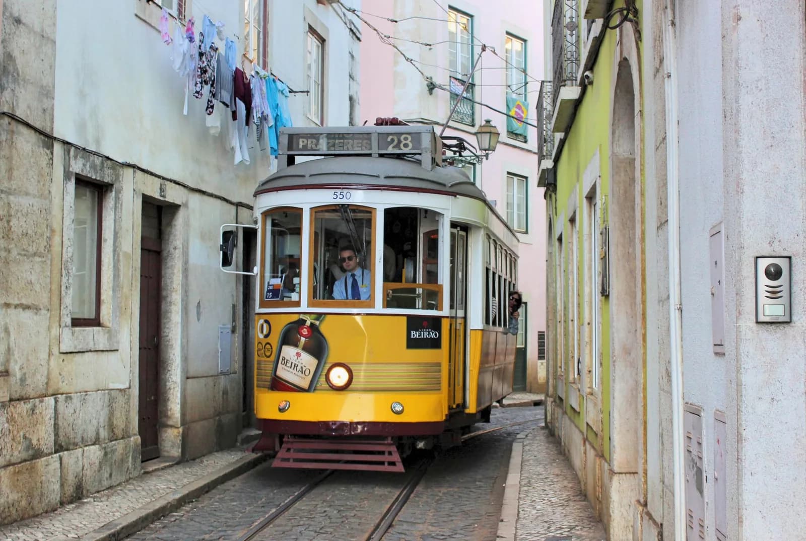 Le tramway 28 jaune dans une rue étroite du vieux Lisbonne, linge aux fenêtres