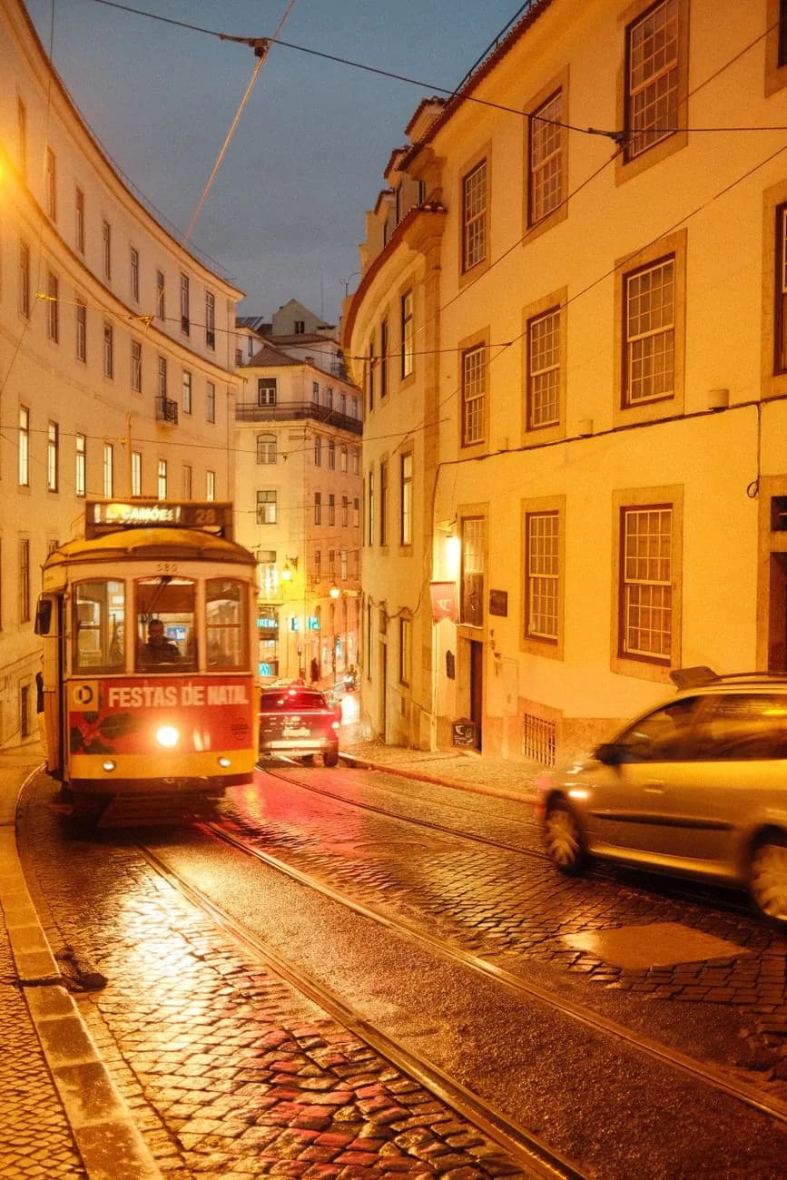 Tram 28 jaune dans une rue pavée de Lisbonne au crépuscule